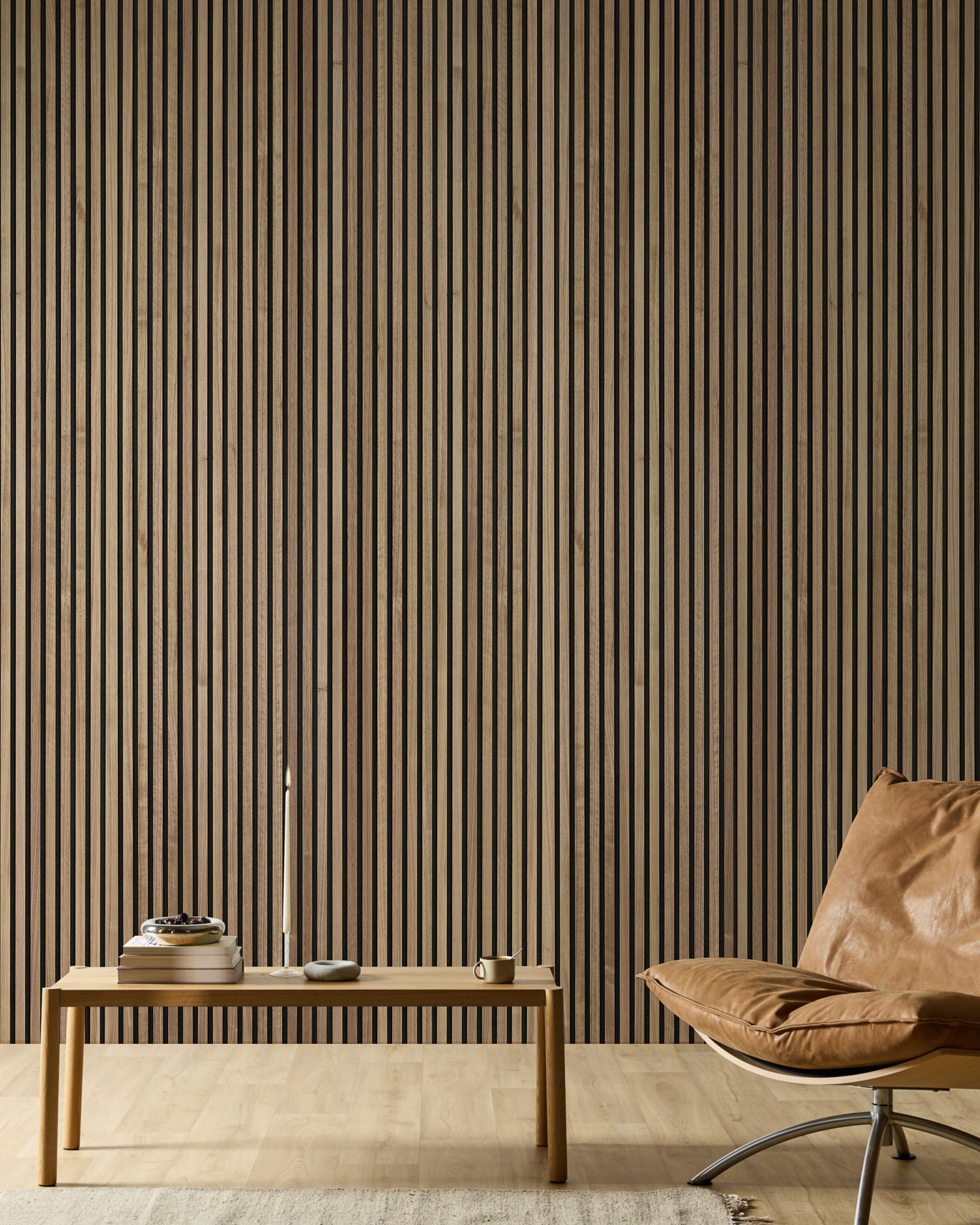 Stanza minimalista con una poltrona in pelle, una panca in legno, libri, una candela e una moderna parete a doghe acustiche in legno Akupanel in toni neutri.